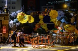 Bystanders peer into barricades and umbrellas attached to an entry to the police headquarters in Hong Kong, June 27, 2019. Hong Kong protesters marched Thursday as they called on G-20 nations to confront China over sliding freedoms in Hong Kong.