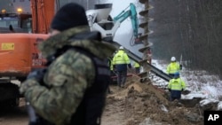 FILE - Workers build the first part of a wall intended to block migrants pushed by Belarus, in what the European Union calls a "hybrid attack," from crossing illegally into EU territory, in Tolcze, near Kuznica, Poland, on the border with Belarus, Jan. 27, 2022.