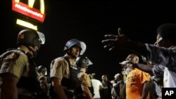 FILE - Officers and protesters face off along West Florissant Avenue in Ferguson, Mo., Aug. 10, 2015.