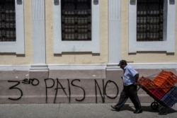 A man carries boxes past the Spanish message: "No third country" near Congress in Guatemala City, July 30, 2019.
