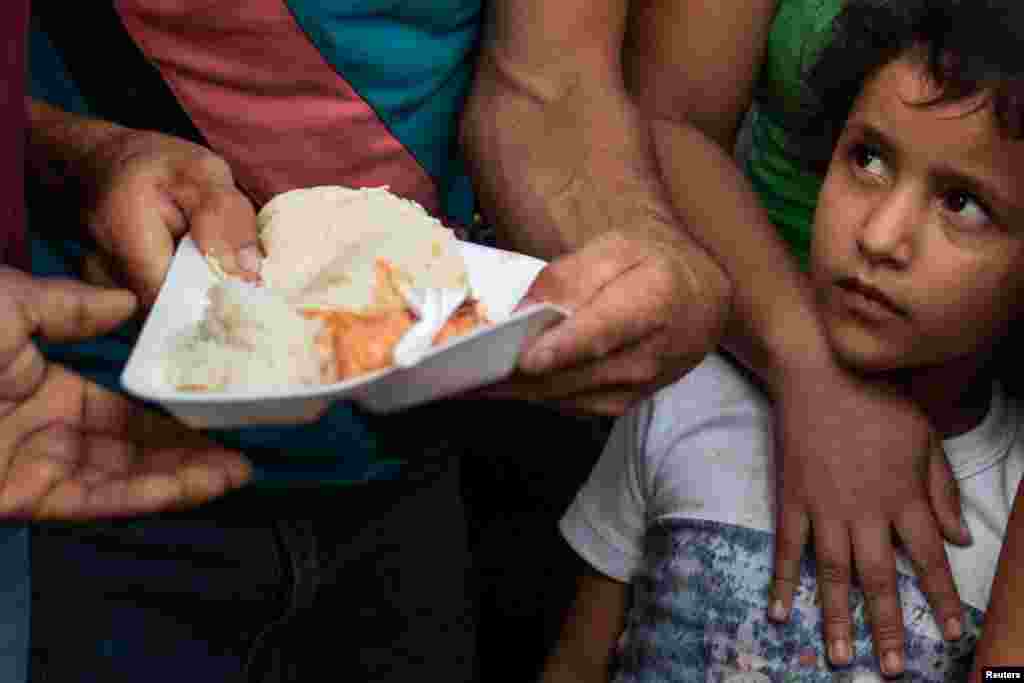A migrant girl, part of a caravan of thousands from Central America en route to the United States, waits to receive food being donated in Huixtla, Mexico, Oct. 23, 2018.