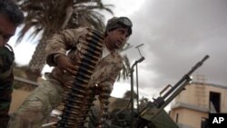 A Libyan army paratrooper who defected and joined the popular uprising against leader Moammar Gadhafi loads an anti-aircraft machine gun atop a truck in the eastern Libyan port city of Benghazi, February 26, 2011