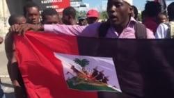 Manifestantes en el la vía del aeropuerto levantan la bandera roja y negra, un gesto desafiante, ya que es un símbolo de la dictadura-la bandera acutal de Haiti de roja y azul desde 1986-