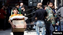 A boy holds a cardboard box of food aid received from World Food Program in Aleppo's Kalasa district, Syria, April 10, 2019.