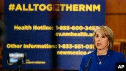 New Mexico Gov. Michelle Lujan Grisham confirms a new coronavirus infection that has no apparent link to travel, March 18, 2020, during a news conference on the floor of the state House of Representatives in Santa Fe, N.M. 