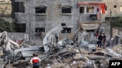 Palestinians check the damage amid the rubble of a destroyed building, following Israeli airstrikes on the northern Gaza Strip town of Beit Lahia, early May 13, 2021.