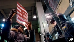 A protester stands facing police officers at an entrance of Terminal 4 at John F. Kennedy International Airport in New York, Jan. 28, 2017, after earlier in the day two Iraqi refugees were detained while trying to enter the country.