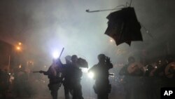 A broken umbrella sails near riot police during a confrontation with protesters in Hong Kong, July 21, 2019.