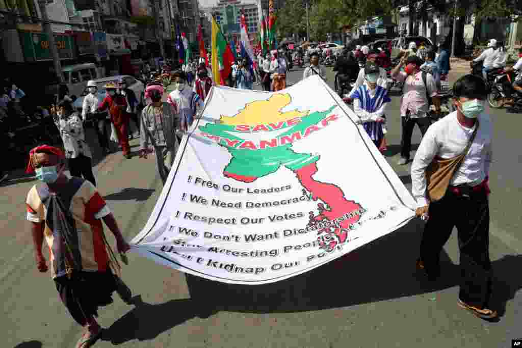 Anti-coup protesters hold a banner which reads: "Save Myanmar" as they march in Mandalay, Feb. 22, 2021.