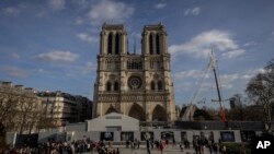 FILE - Scaffolding is being removed around the spire of Notre Dame de Paris cathedral, showing the rooster and the cross, in Paris, Feb. 17, 2024. 