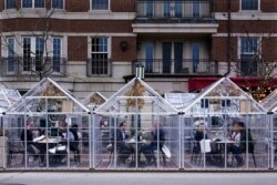 FILE - Diners eat in isolated rooms outside the Townhouse restaurant, in Birmingham, Mich., March 25, 2021. While many people are eager to discard this kind of protection, others will hesitate about the transition back to a new normal.