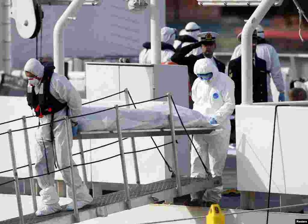 Italian Coast Guard personnel in protective clothing carry the body of a dead immigrant off their ship, Bruno Gregoretti, in Senglea, in Valletta&#39;s Grand Harbor, April 20, 2015.