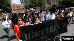 People carry a banner as they take part in events to mark Juneteenth, which commemorates the end of slavery in Texas, two years after the 1863 Emancipation Proclamation freed slaves elsewhere in the United States