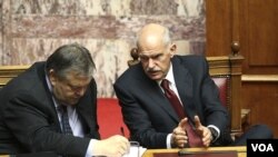 PM Yunani George Papandreou (kanan) berbicara dengan Menkeu Evangelos Venizelos saat memberikan keterangan di depan anggota parlemen Yunani di Athena (30/6).