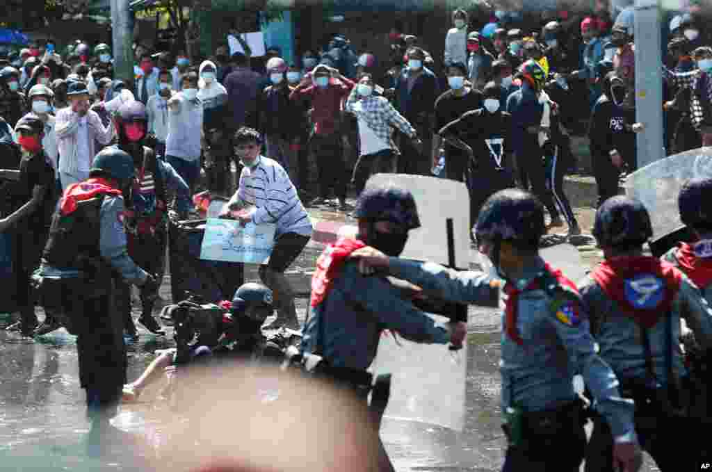 Protesters run after police fire warning-shots and use water cannons to disperse them during a protest in Mandalay, Myanmar, Feb. 9, 2021. 