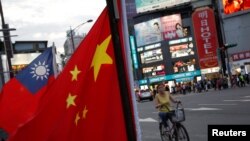 资料照：一名台湾妇女骑车从台北街头举行的台湾亲中国组织呼吁和平统一的一个集会前驶过。（2016年5月14日）