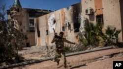 FILE - A fighter of the Libyan forces, affiliated with the Tripoli government, runs for cover while fighting against Islamic State positions in Sirte, Libya, Sept. 22, 2016. IS forces have since been dispersed, yet they can thrive in porous security conditions like those that exist today in Libya, said Frederic Wehrey, a senior fellow at the Carnegie Endowment for International Peace.