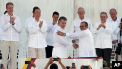 Colombia’s President Juan Manuel Santos, front left, and the top commander of the Revolutionary Armed Forces of Colombia (FARC) Rodrigo Londono, shake hands after signing the peace agreement between Colombia’s government and the FARC to end over 50 years of conflict in Cartagena, Colombia, Sept. 26, 2016.