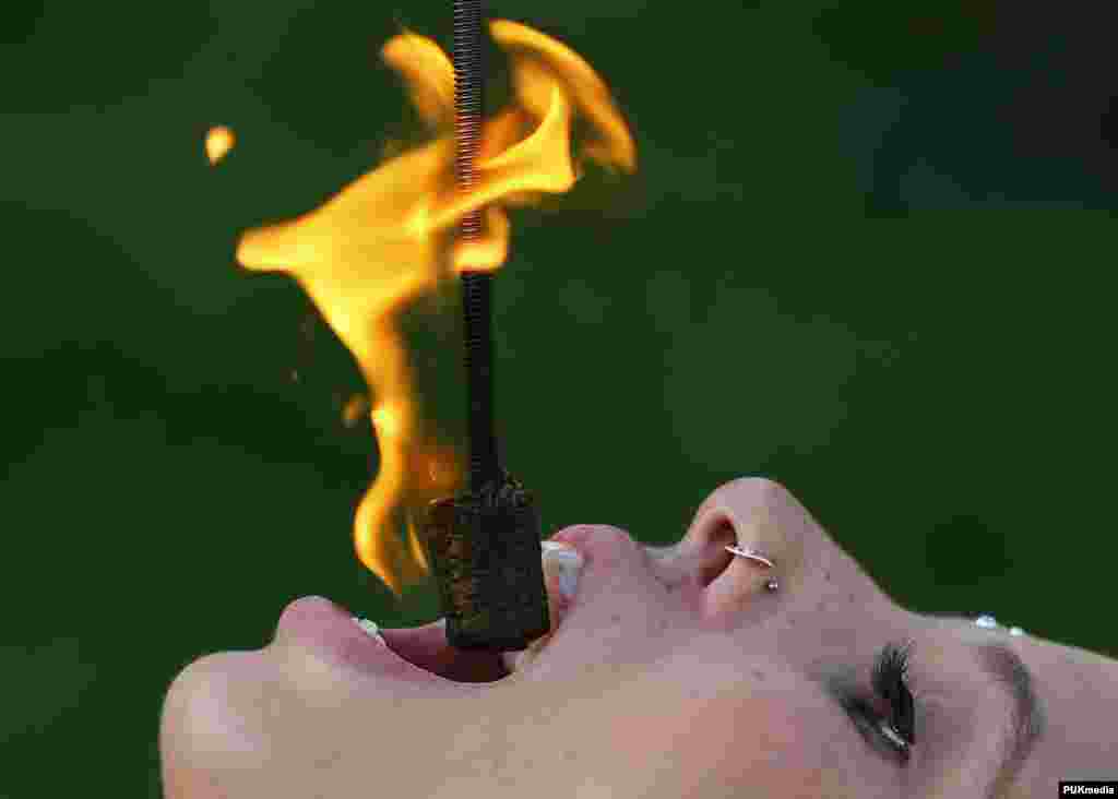 Street performer Kristin Decker performs a fire-eating act before the opening ceremonies for the 2013 Presidents Cup golf tournament in Columbus, Ohio, USA, Oct. 2, 2013. 