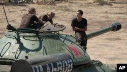 Ukrainian government soldiers sit atop of a tank with the words reading "To Lviv" in Donetsk region, eastern Ukraine, Saturday, Aug. 9, 2014.