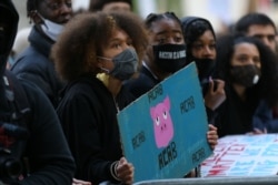 A protester holds an anti-police placard as she joins others outside Downing Street in central London after attending a demonstration outside the U.S. Embassy, on June 7, 2020.