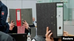 FILE - Two men accused of fighting with the co-called Islamic State militant group hide their faces before their trial in Germany November 30, 2015.