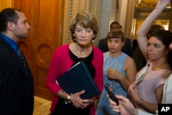 FILE - In this July 28, 2017, file photo, Sen. Lisa Murkowski, R-Alaska, passes reporters as she leaves the Senate chamber on Capitol Hill in Washington. Conservatives across the country warned that the GOP-led Congress could not abandon its pledge to repeal and replace Obamacare without suffering losses in the next election.