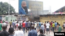 FILE - Congolese opposition supporters chant slogans as they deface a billboard of President Joseph Kabila during a march calling on him to step down at the end of his term, in the Democratic Republic of Congo's capital Kinshasa, Sept. 19, 2016.