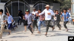 Cambodian garment workers run for safety in front of a factory of Yak Jin in Kambol village on the outskirts of Phnom Penh, Cambodia, Jan. 2, 2014.