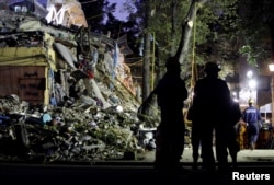 Rescue workers stand next to the rubble of a collapsed multi family residential, after an earthquake, in Mexico City, Mexico, Sept. 24, 2017.