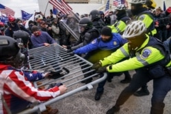 FILE - In this Jan. 6, 2021, photo, rioters try to break through a police barrier at the Capitol in Washington.