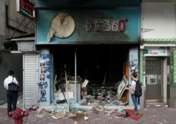 FILE - A man inspects a Bestmart store that was vandalized during anti-government protests in Hong Kong, Oct. 21, 2019.