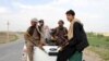 Afghan local police (ALP) sitting at the back of a truck drive past a checkpoint at Chardara district, in Kunduz province, Afghanistan, June 23, 2015.