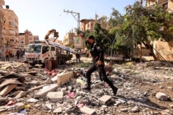 A member of the Palestinians Hamas security forces walks in the midst of damage caused by an Israeli airstrike in the town of Khan Yunis, in the southern Gaza Strip, on May 12, 2021.