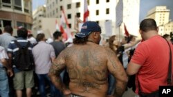 Activists hold flags and chant slogans in front of the government house during a protest against the ongoing trash crisis, in downtown Beirut, Lebanon, Tuesday, Aug. 25, 2015.