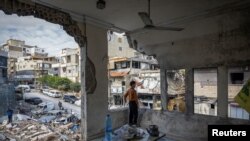 A 10-year-old boy stands inside his house damaged in an Israeli strike, after the ceasefire between Israel and Hezbollah, in Tyre, southern Lebanon, Nov. 29, 2024.