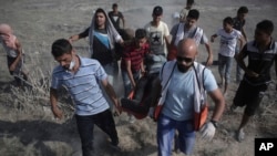 Palestinian medics and protesters evacuate an injured man during clashes with Israeli soldiers on the Israeli border with Gaza, July 21, 2017. An escalating dispute over metal detectors at a contested Jerusalem shrine turned violent on Friday, setting off widespread clashes.