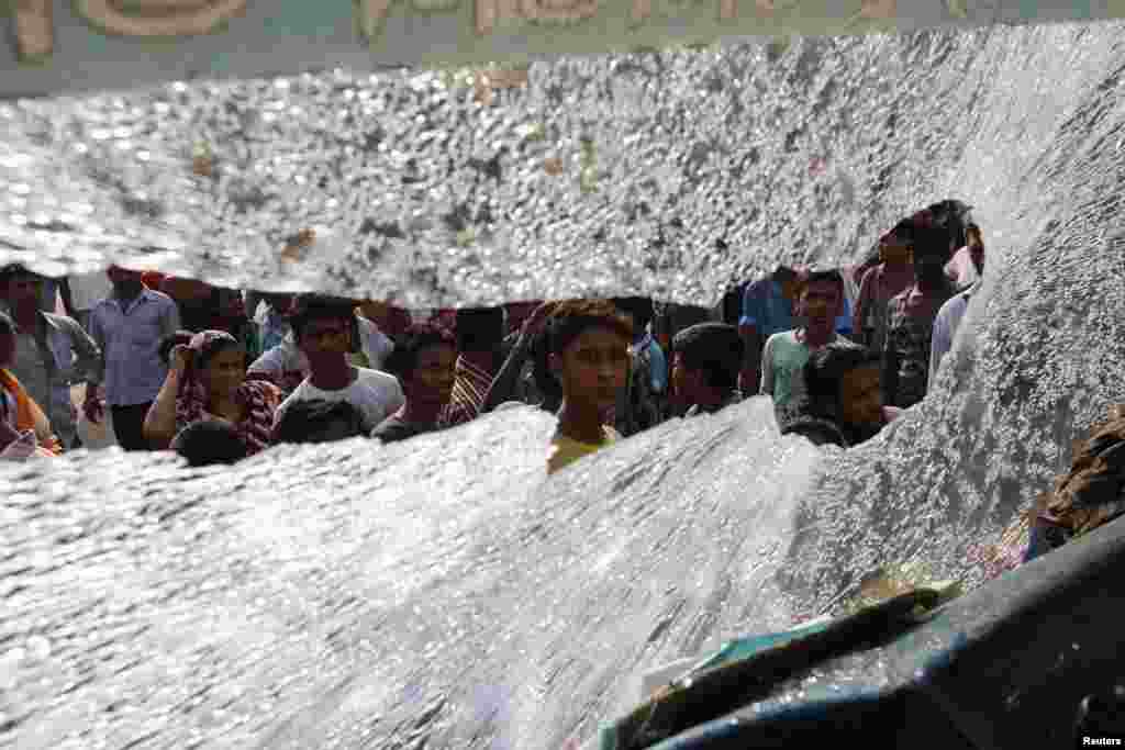 Warga Bangladesh melakukan aksi protes di Dhaka terlihat dari kaca jendela bus yang pecah.