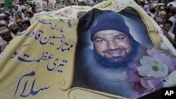 Supporters of religious group Sunni Tehreek hold a huge poster of Mumtaz Qadri, the confessed killer of a liberal Pakistani governor, during a rally to condemn the court decision against Qadri, October 1, 2011 in Karachi.