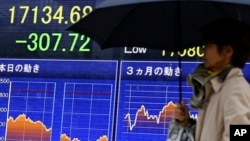 People walk past an electronic board showing the Nikkei stock index in Tokyo, Nov. 2, 2016.