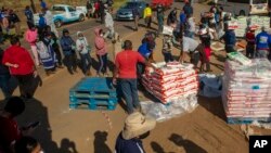 Wasu mutane da annobar Coronavirus ta shafa lokacin da suke karban tallafin abinci a kusa da Laudium, kudu maso yammacin Pretoria, a Afirka ta Kudu, ranar 20 ga watan Mayun 2020.