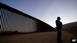 FILE - Border Patrol agent Justin Castrejon speaks in front of newly replaced border wall sections, Sept. 24, 2020, near Tecate, Calif. 