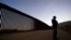 FILE - Border Patrol agent Justin Castrejon stands in front of newly replaced border wall sections, near Tecate, California, Sept. 24, 2020.