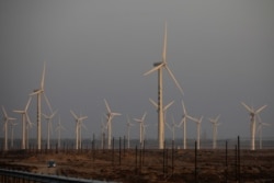 FILE - A car drives near wind turbines on a power station near Yumen, Gansu province, China, September 29, 2020.