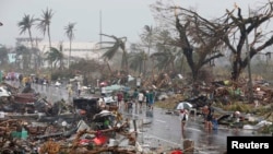 Residents walk on a road littered with debris after Super Typhoon Haiyan battered Tacloban city in central Philippines Nov. 10, 2013.