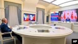 Russian President Vladimir Putin, left, attends a video conference with Turkish President Recep Tayyip Erdogan and Iranian President Hassan Rouhani in Moscow, Russia, July 1, 2020.