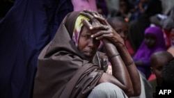 FILE -In this photo released by the AU-UN Information Support Team Aug. 31, 2013, a woman and children wait to see a doctor at a free medical clinic in the southern Somali port city of Kismayo. The clinic treats a variety of illnesses, including malaria. 