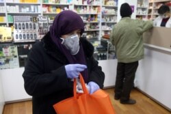 FILE - An Iranian woman wears a protective mask to prevent contracting coronavirus, as she is seen at a drug store in Tehran, Iran, Feb. 25, 2020.