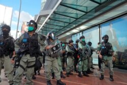 Police stand guard outside a mall where mourners pay their respects on the one year anniversary at the site where a man fell to his death after hanging a protest banner, in Hong Kong, June 15, 2020.