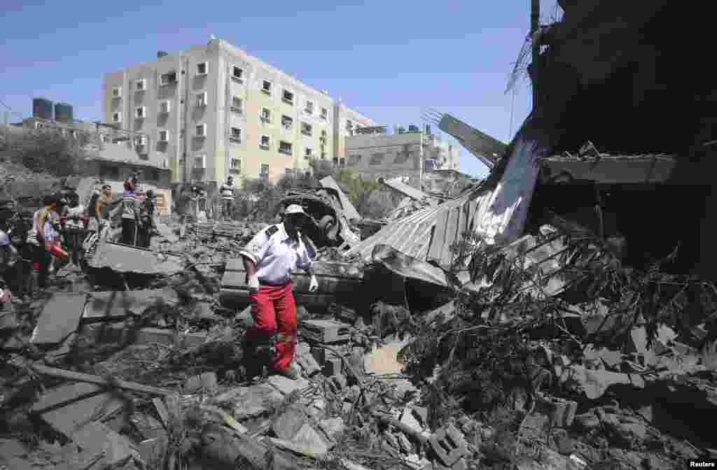 A Palestinian medic walks amidst the debris of a house which police said was destroyed in an Israeli air strike in Rafah in the southern Gaza Strip July 14, 2014.